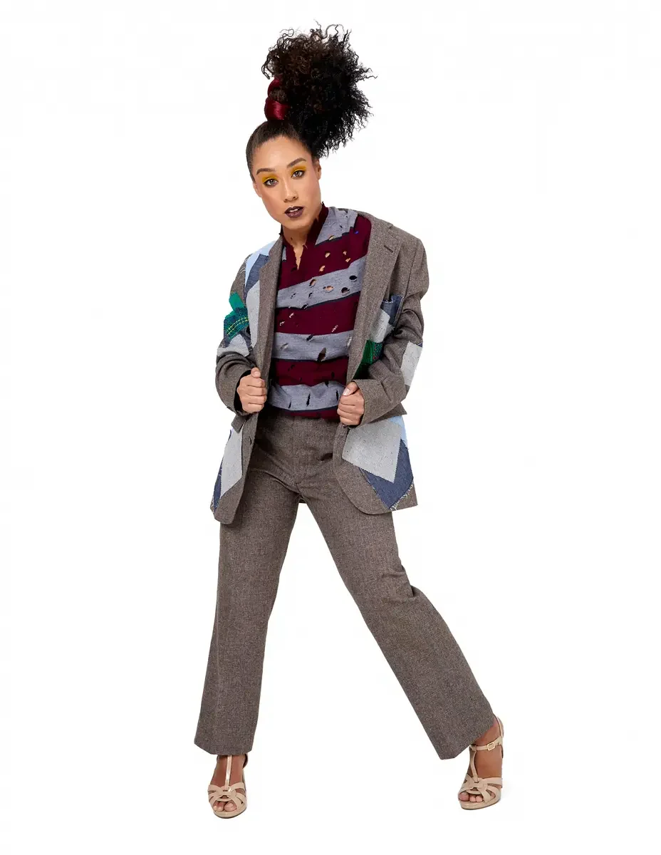 Model portfolio development session, high fashion editorial look, oversized heathered blazer with mixed fabric appliqué panels over burgundy and heather grey destroyed-knit stripe sweater with raw-edge sleeves, straight-leg heathered trousers, nude t