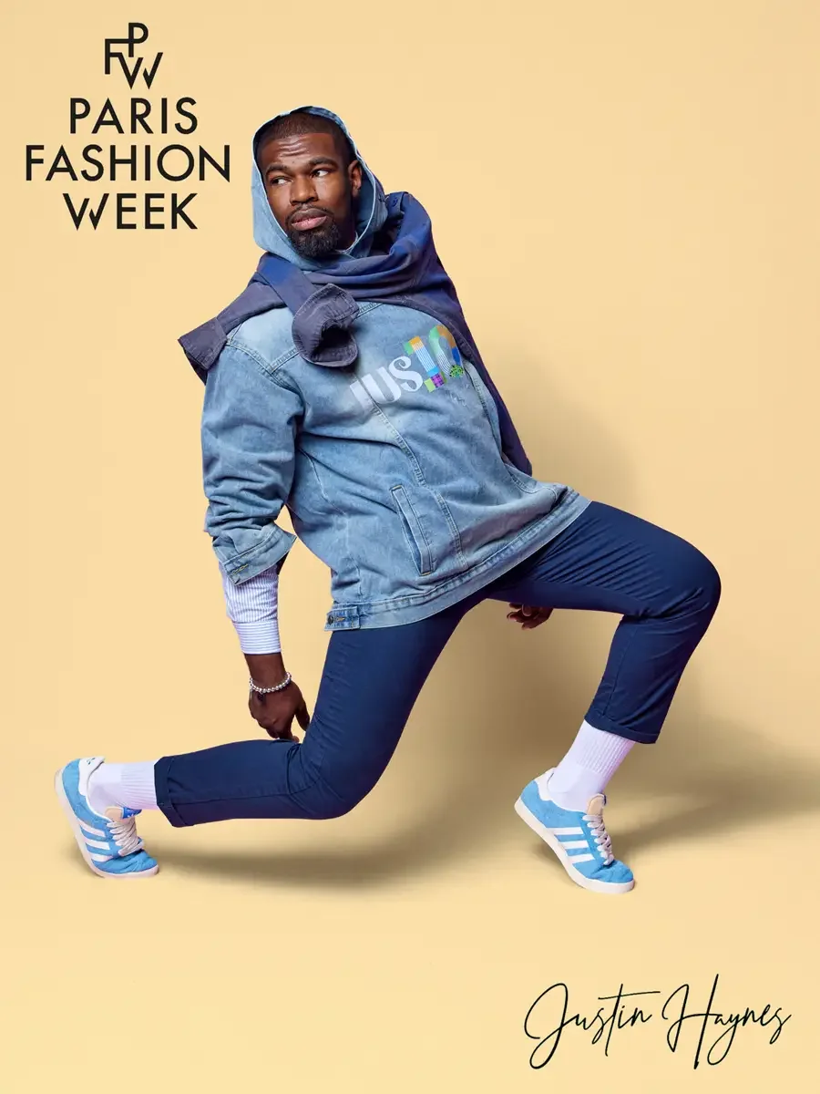 JUS10H 2025 promotional image, model in dynamic lunge pose wearing light wash JUS10H logo denim jacket layered over navy hoodie and striped shirt, navy JUS10H script trousers, white socks and sky blue sneakers, butter yellow background, photographed 