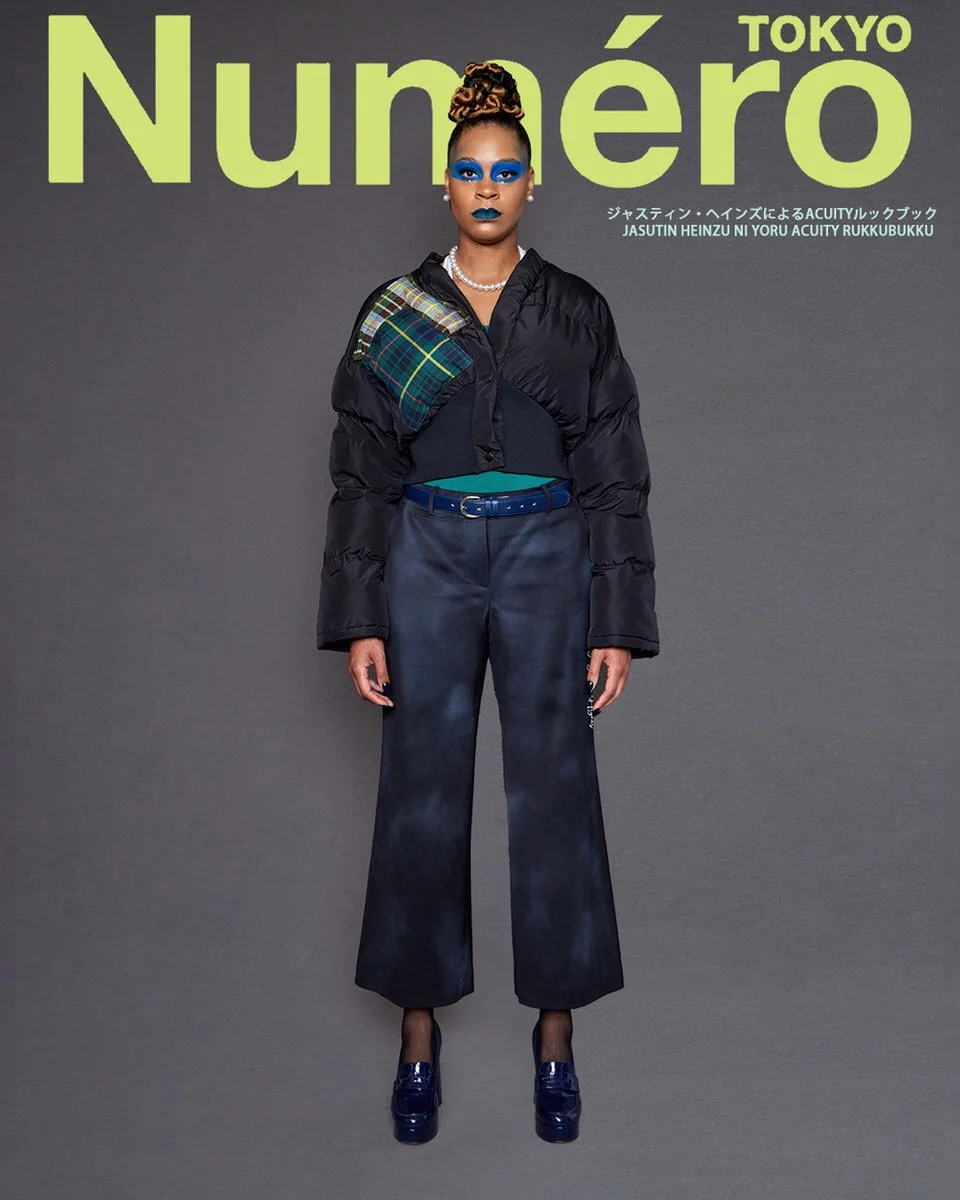 JUS10H by Justin Haynes ACUITY Collection lookbook for Numéro Tokyo by Scott Parker — model in cropped black puffer jacket with green tartan patchwork shoulder, layered over teal top with navy belt, paired with iridescent navy wide-leg trousers, fish