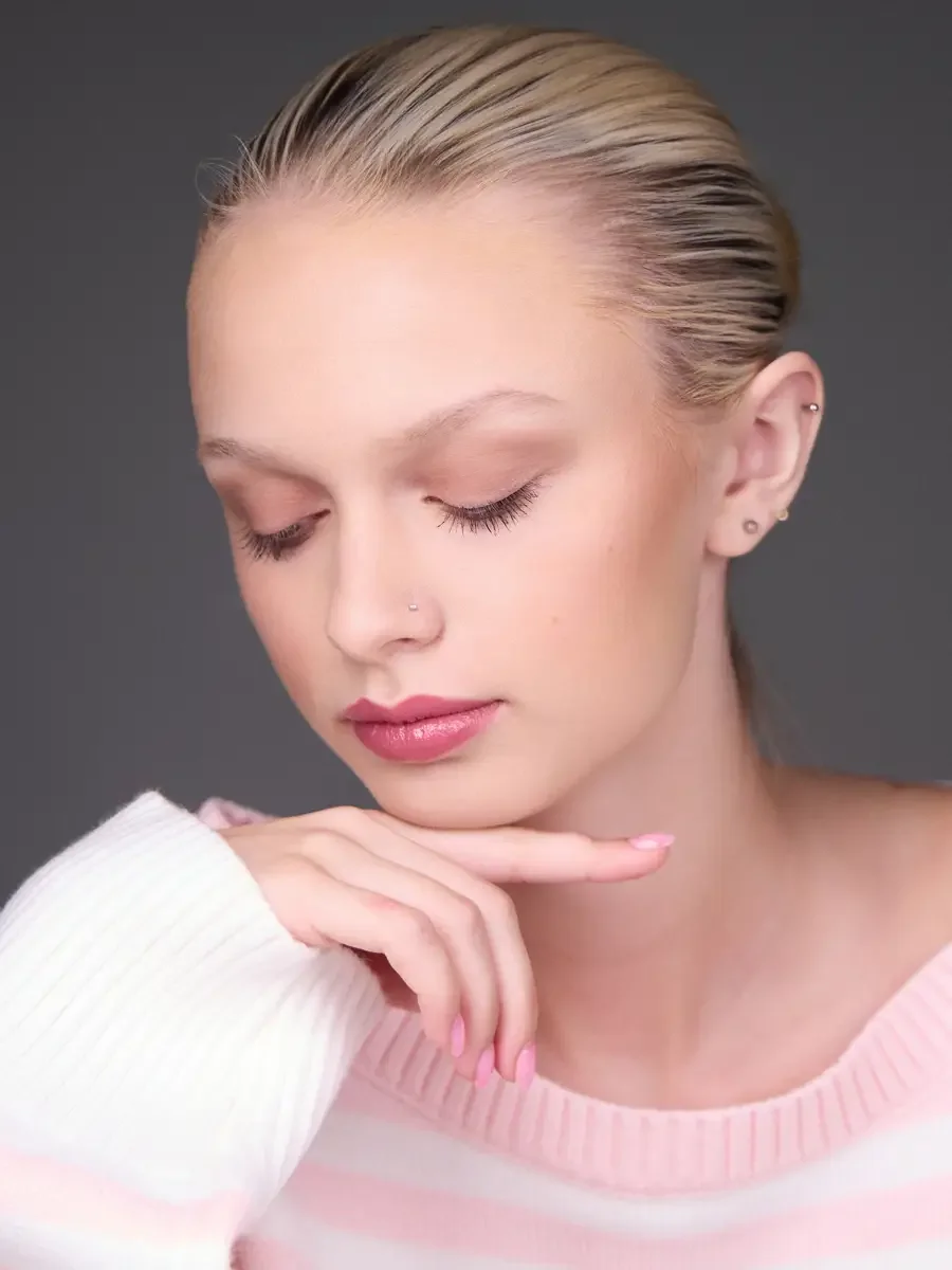 Model portfolio development session, beauty, close-crop, hair slicked back, three-quarter turn, eyes closed, hand at chin, rose lip, soft eye, pink striped sweater, gray background, photographed by Scott Parker Photo, New York