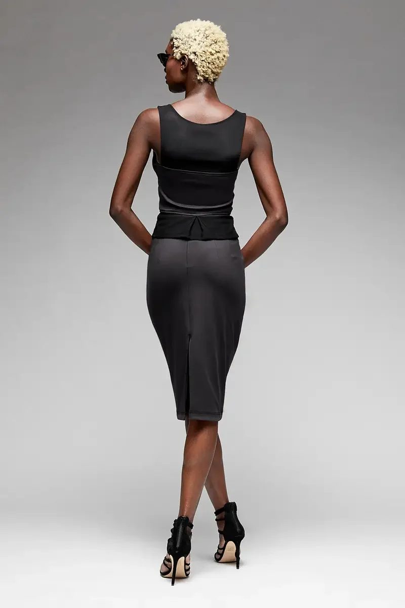 Minika Ko lookbook, black zip-front corset top and fitted pencil skirt, back view, scoop back neckline, peplum ruffle at waist, center back vent at hem, smooth synthetic fabric, dark sunglasses, photographed by Scott Parker Photo
