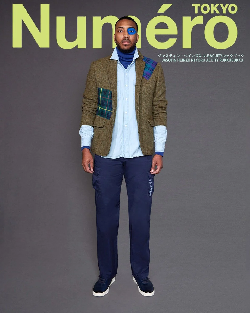 JUS10H by Justin Haynes ACUITY Collection menswear look for Numéro Tokyo by Scott Parker — male model in olive herringbone tweed blazer with multi-tartan patchwork pockets and shoulder, layered over chambray button-down and royal blue turtleneck, pai