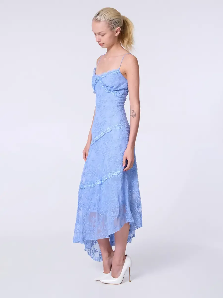 Model portfolio development session, commercial look, periwinkle blue lace asymmetrical midi dress with ruffle bodice detail and spaghetti straps, full-length, profile turn, gaze downward, arms at sides, sheer lace hem panel and diagonal tier lines c
