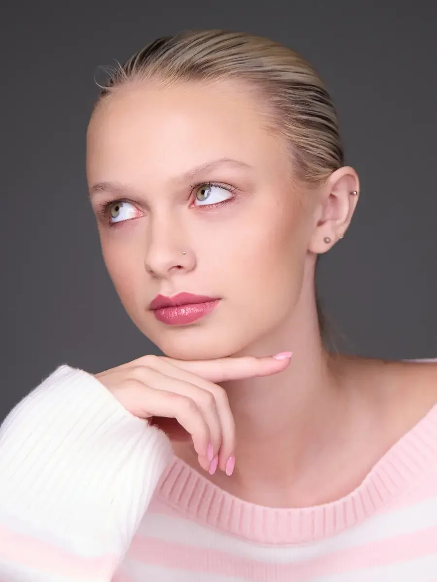 Model portfolio development session, beauty, close-crop, hair slicked back, slight turn, gaze directed left, eyes up, hand at chin, rose lip, soft eye, pink striped sweater, gray background, photographed by Scott Parker Photo, New York