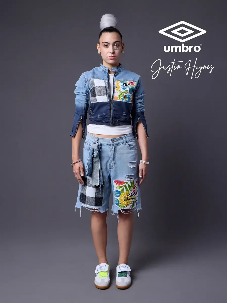 Lookbook photography for the Umbro France collection. Vanessa standing front-facing in a cropped two-tone denim moto jacket with floral patchwork panels and matching distressed denim bermuda shorts, styled by Justin Haynes, photographed in Springfiel