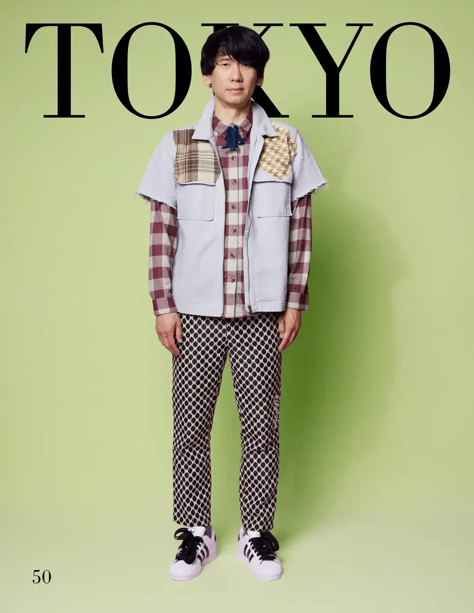 JUS10H 2025 Tokyo lookbook, a male model wearing a pale periwinkle blue sleeveless denim vest with mixed plaid and houndstooth patchwork chest panels and raw-hem edges, over a burgundy and white large-check flannel shirt, black and cream geometric pr