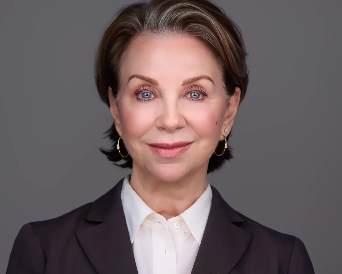 Executive headshot, senior leader in dark blazer and white shirt, authoritative and approachable expression, gray background, photographed by Scott Parker Photo