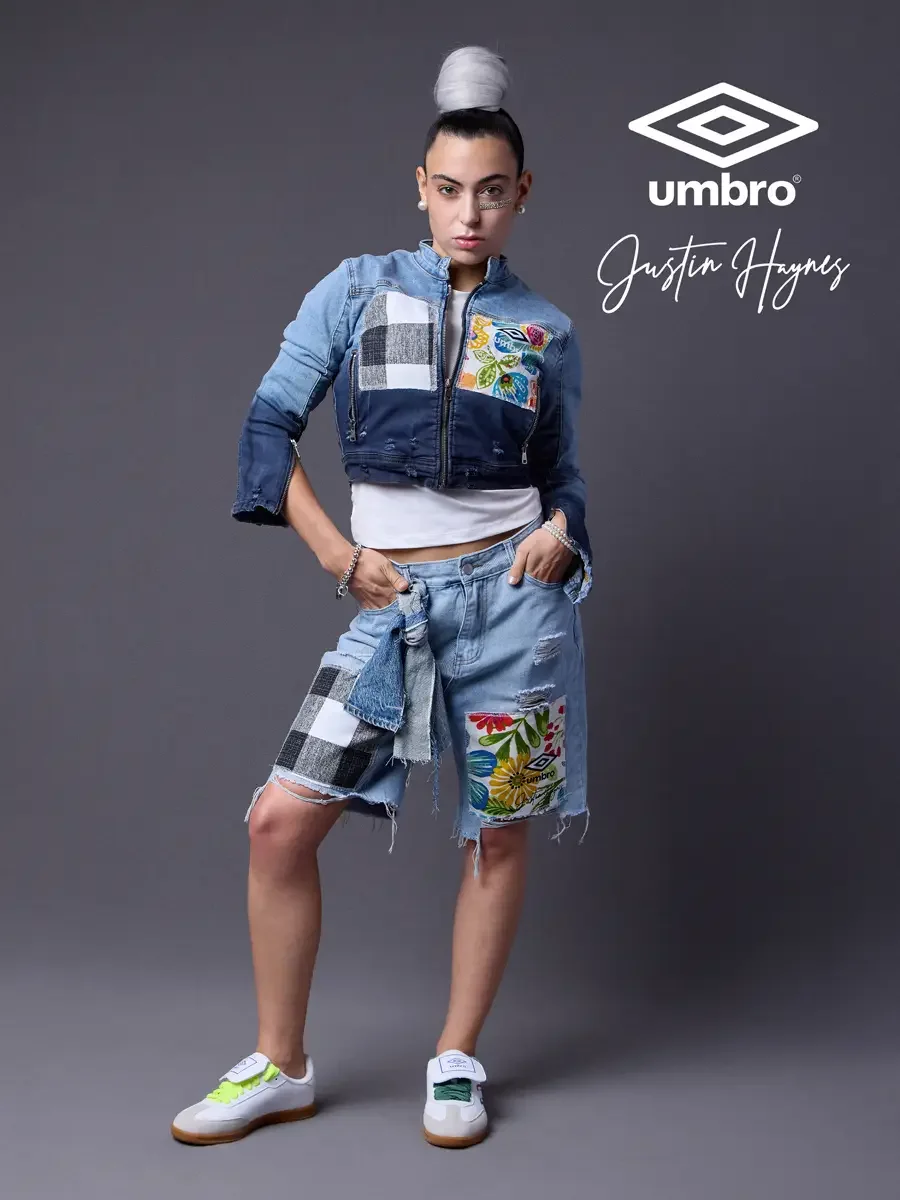Refined football style for the Umbro France collection. Vanessa standing with hands in pocket in a cropped two-tone denim moto jacket with floral patchwork panels and matching distressed denim bermuda shorts, styled by Justin Haynes, photographed in 