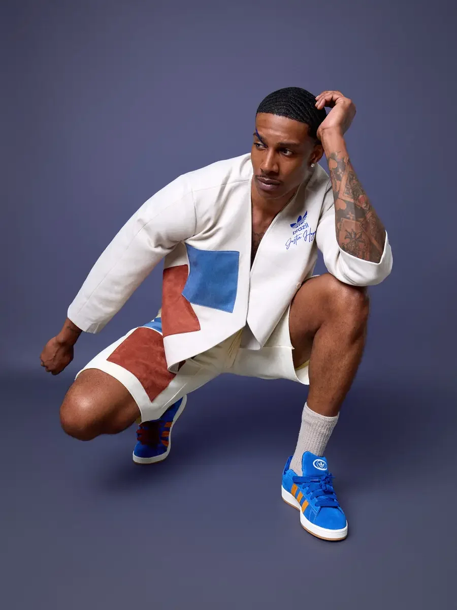 JUS10H x Adidas Brasil campaign, model in low squat with hand raised to head, white patchwork open robe jacket with blue and terracotta suede panels over cream patchwork shorts, Adidas Campus 00s in royal blue suede with orange stripes, periwinkle ba