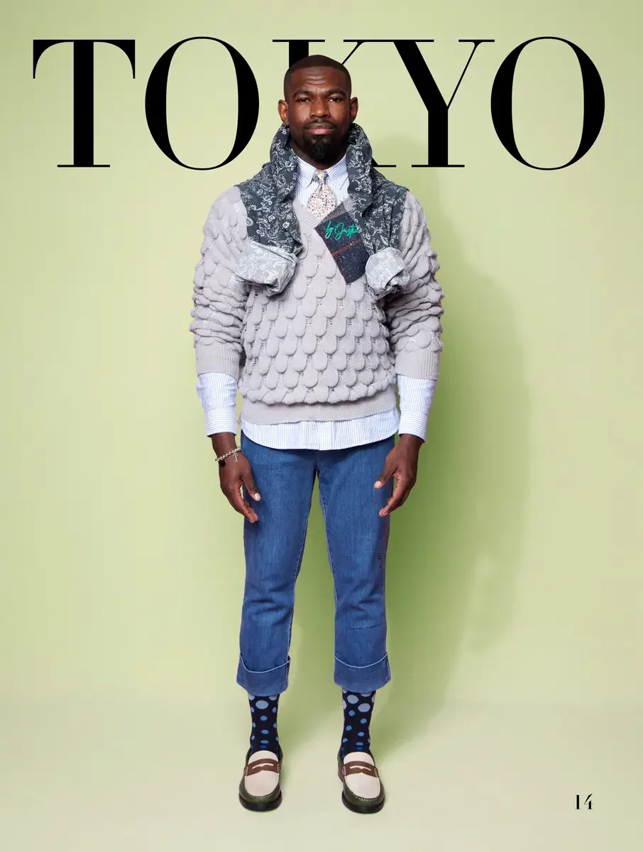 JUS10H 2025 Tokyo lookbook, grey bubble texture sweater with paisley scarf and denim pocket detail over blue striped shirt and cropped jeans with polka dot socks, sage green background, photographed by Scott Parker Photo for the Tokyo Fashion Council