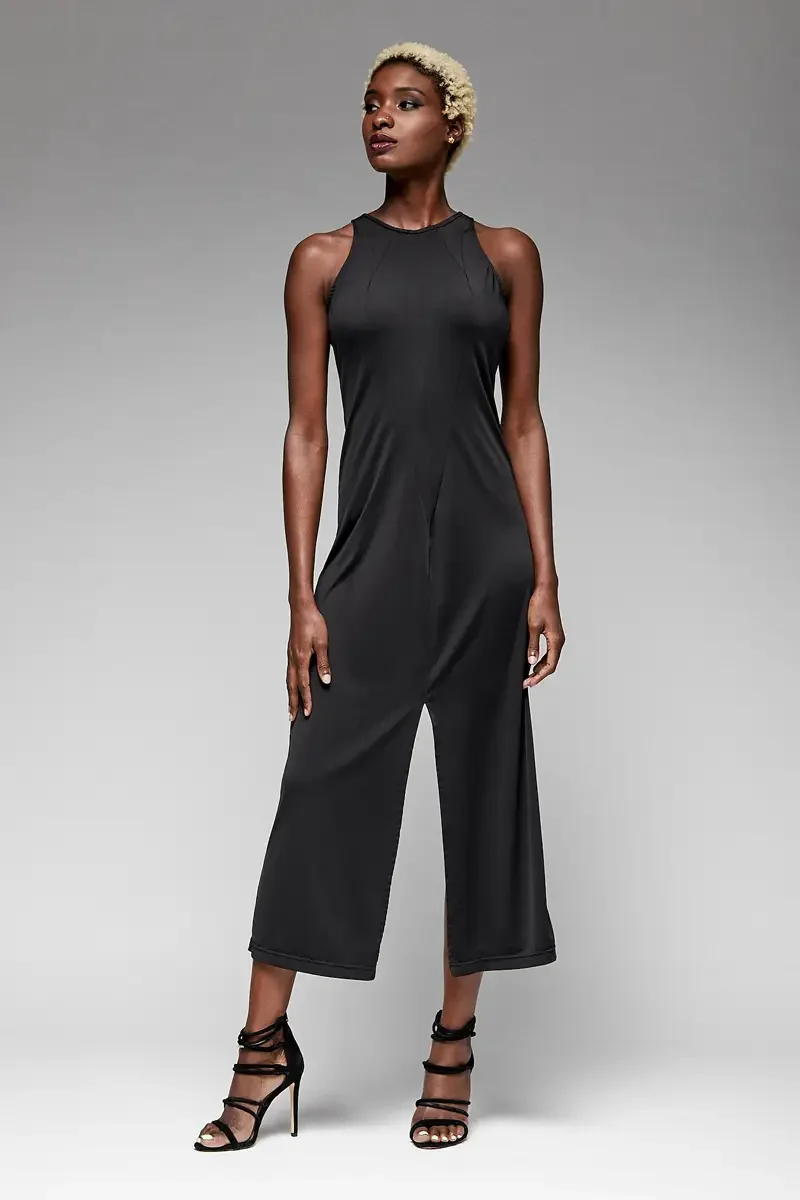 Minika Ko lookbook, black sleeveless jumpsuit, front view, high halter neckline with angled seam detail at shoulder, relaxed wide-leg silhouette, center front seam, smooth synthetic fabric, photographed by Scott Parker Photo