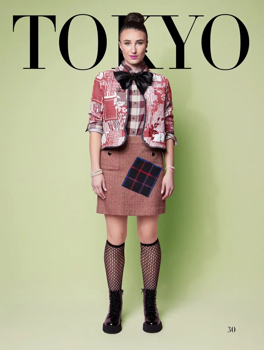 JUS10H 2025 Tokyo lookbook, red and white toile print cropped jacket with black satin bow over plaid shirt and pink tweed mini skirt with tartan patch and fishnet knee socks with patent lace up boots, sage green background, photographed by Scott Park