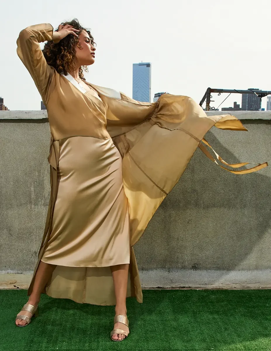 Fashion test shoot, full-length, model Ireland T in a gold satin wrap dress, skirt lifting in the wind, Manhattan skyline, East Village rooftop, New York City, styling by Matsine Stinson, makeup by Stefani Paige Vivian, photographed by Scott Parker P