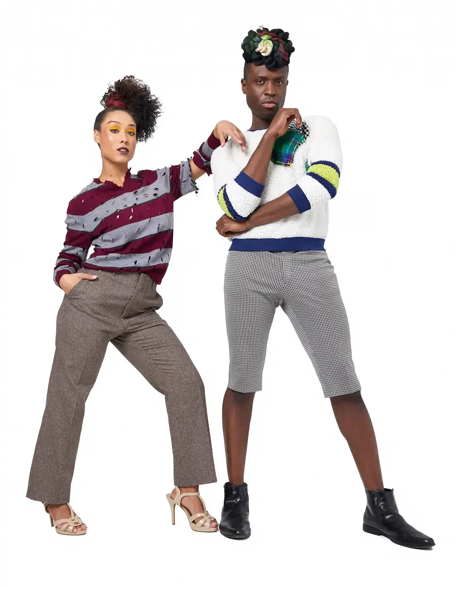 Model portfolio development session, high fashion editorial look, two models side by side, woman in burgundy and heather grey destroyed-knit stripe sweater and straight-leg heathered trousers, man in white patchwork bouclé knit sweater and houndstoot