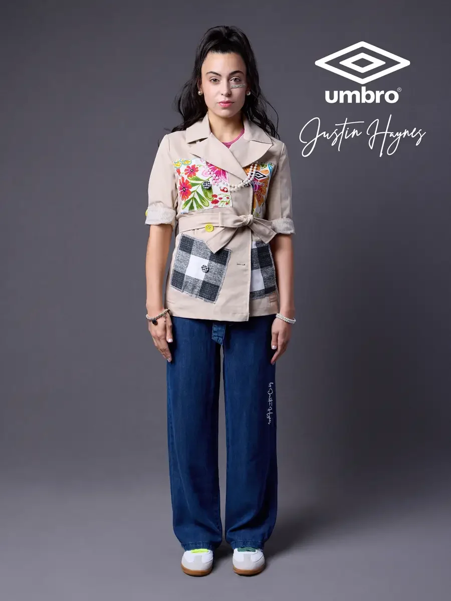 Fashion brand photography for the Umbro France collection. Vanessa standing front-facing with jacket belted in a sand utility jacket with floral patchwork panels over a fuchsia t-shirt and wide-leg dark indigo jeans, styled by Justin Haynes, model Va