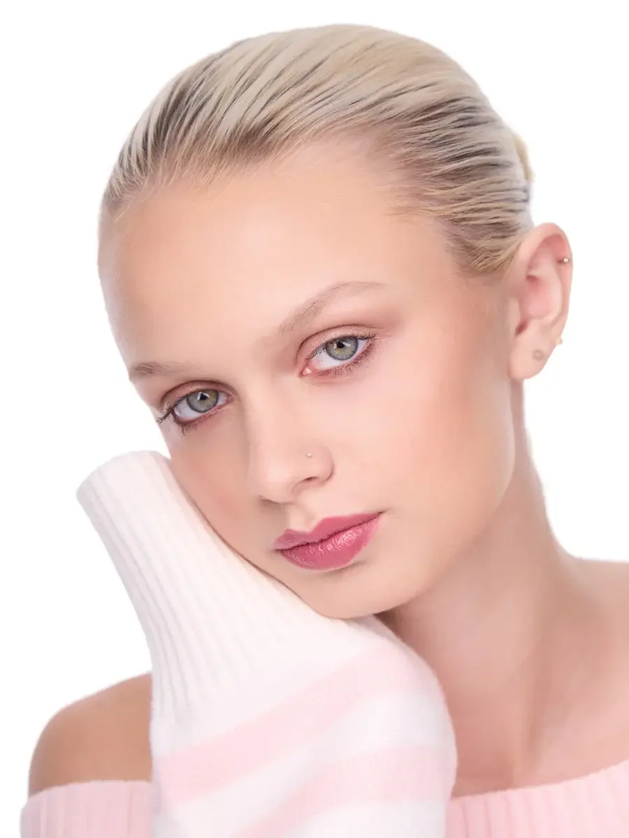 Model portfolio development session, beauty, close-crop, hair slicked back, three-quarter turn, direct gaze, rose lip, soft eye, pink ribbed sweater held against cheek, white background, photographed by Scott Parker Photo, New York