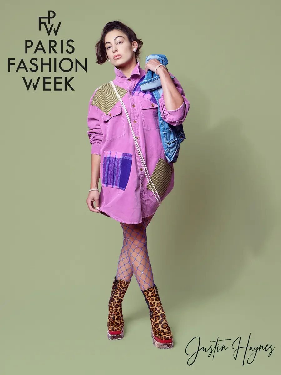 JUS10H 2025 promotional image, model in fuchsia oversized patchwork denim shirtdress with olive houndstooth and purple tartan panels, pearl rope necklace, blue rhinestone fishnet tights and leopard print platform boots, light blue denim jacket draped