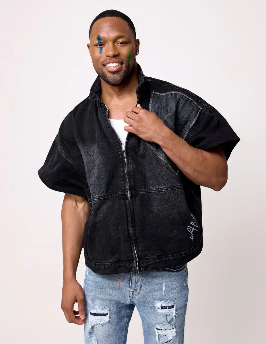 JUS10H Black Summer Jacket editorial, three-quarter portrait of male model in black denim wide-shoulder zip jacket with gray patchwork panels, distressed light-wash jeans, white background, photographed by Scott Parker Photo