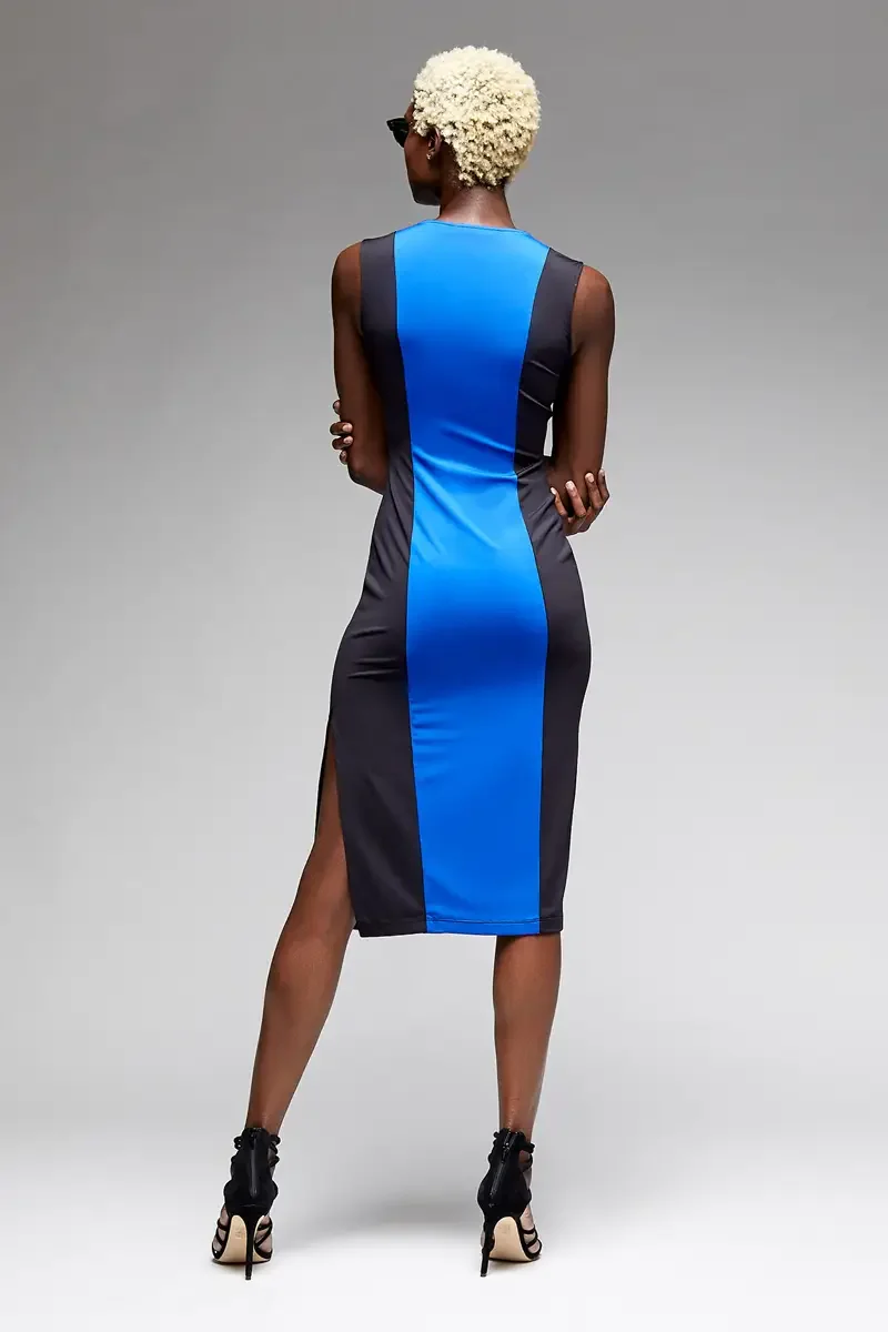 Minika Ko lookbook, cobalt blue and charcoal color-block sleeveless midi dress, vertical center panel in cobalt with charcoal side panels, smooth matte-finish semi-water-repellent synthetic, back view, side slits, black strappy heeled sandals, gray b
