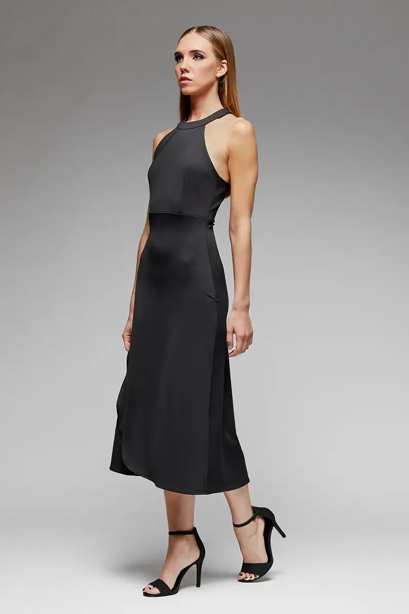 Minika Ko lookbook, black halter midi dress, three-quarter view, high halter neckline with strap detail, horizontal seam at waist, flared A-line skirt, smooth synthetic fabric, photographed by Scott Parker Photo
