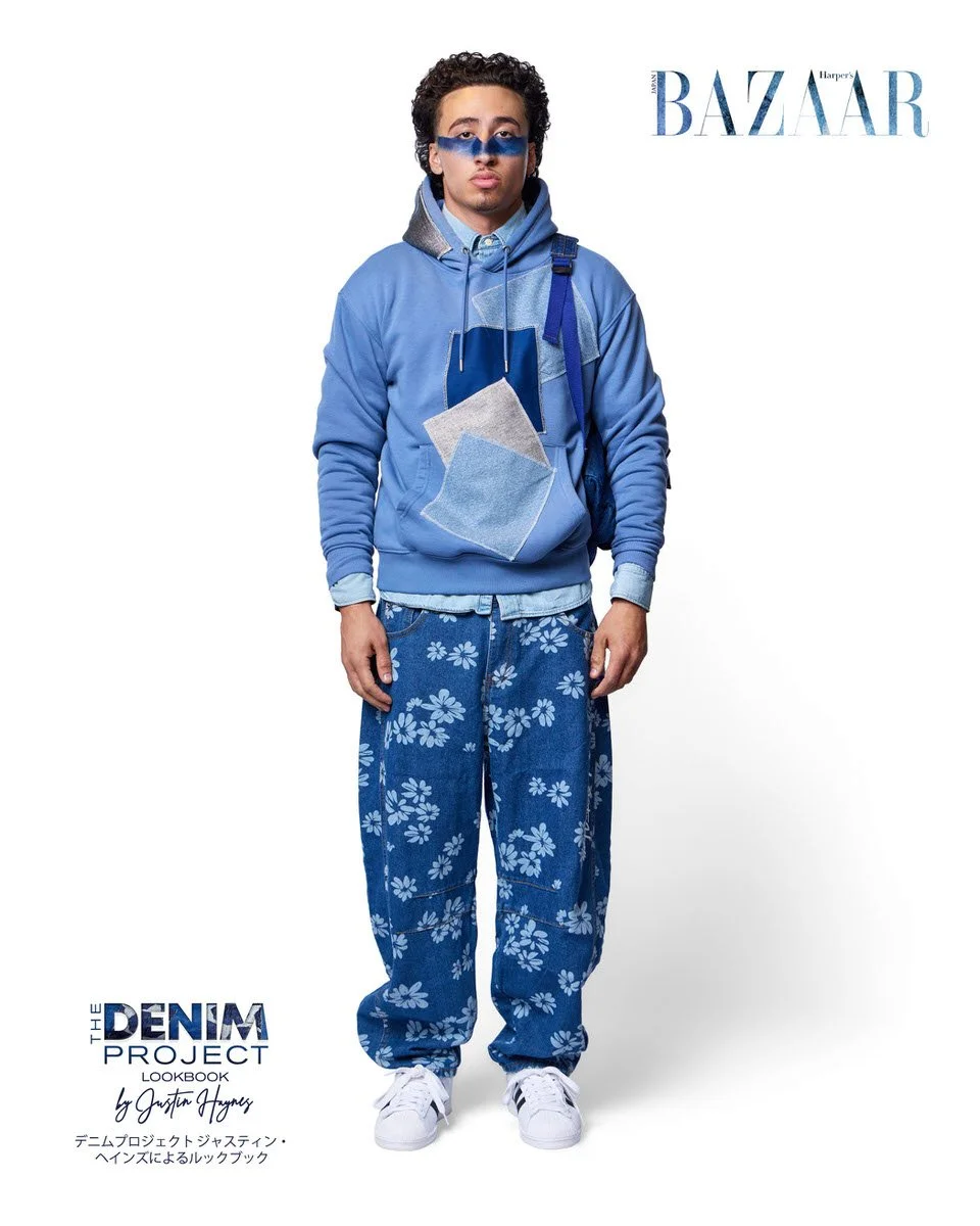 JUS10H Denim Project 2025 Harper's Bazaar Japan lookbook — male model in periwinkle blue denim-patchwork hoodie with grey flannel and indigo appliqué panels over floral-print dark indigo wide-leg jeans, light blue denim shirt underlayer, blue backpac