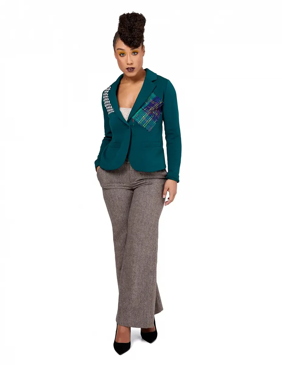 Model portfolio development session, high fashion editorial look, teal single-button blazer with houndstooth and multicolor tweed appliqué panels, wide-leg heather tan orange trousers, black stiletto heels, full-length, weight shifted, one hand in po