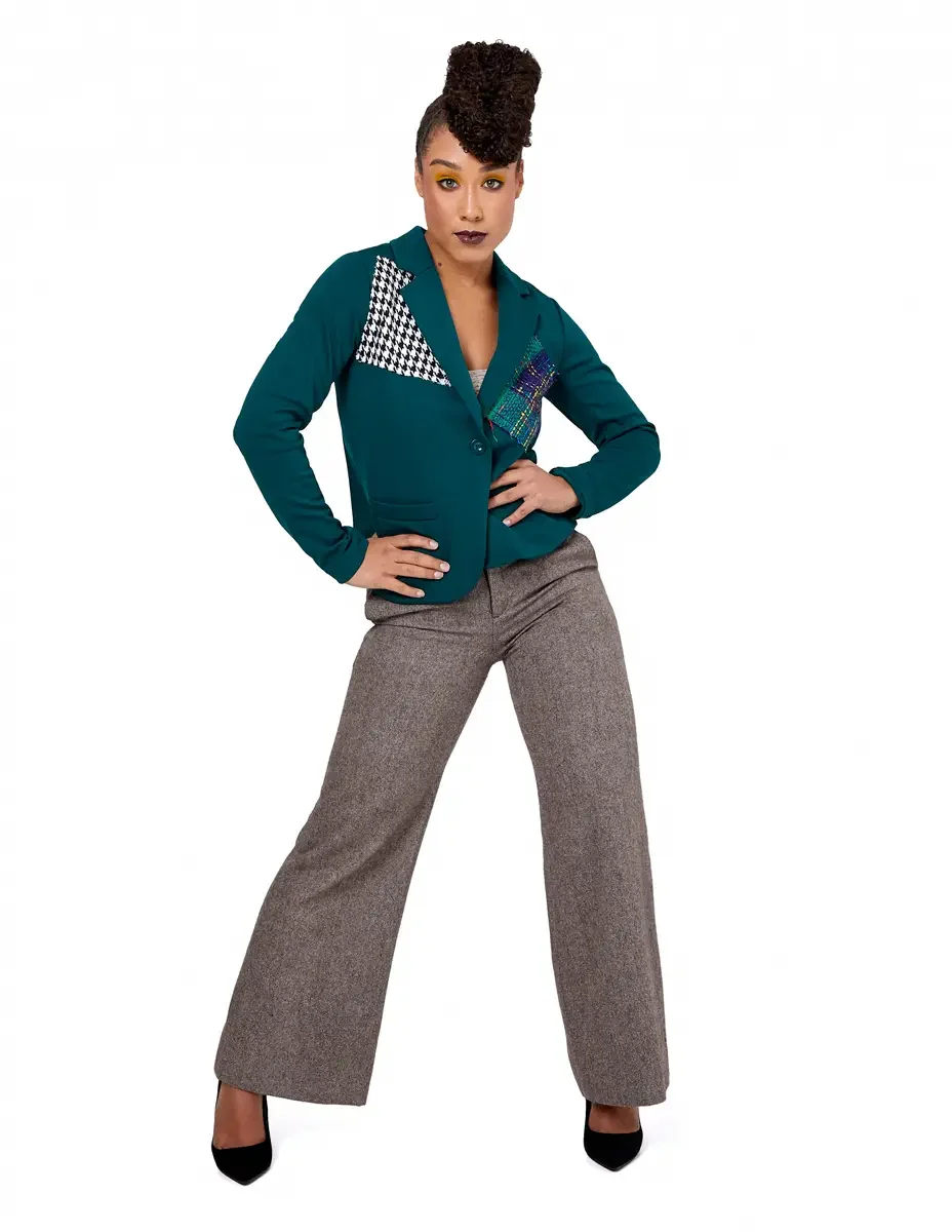 Model portfolio development session, high fashion editorial look, teal single-button blazer with houndstooth and multicolor tweed appliqué panels, wide-leg heather orange trousers, black stiletto heels, full-length, hands on hips, wide stance, direct