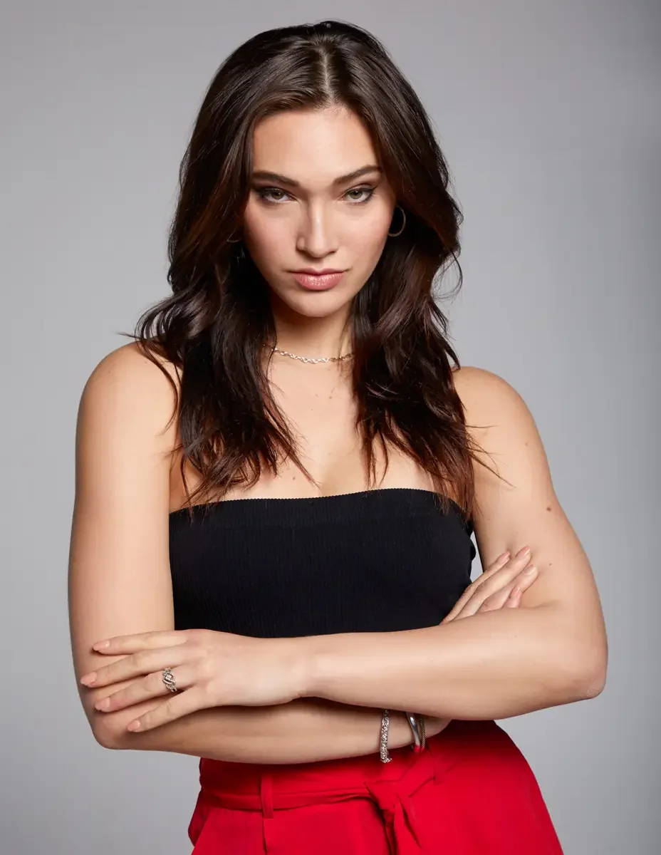 Model portfolio development session, commercial portrait, black ribbed tube top, red wide-leg trousers, silver jewelry, arms crossed, direct gaze, gray background, photographed by Scott Parker Photo, New York