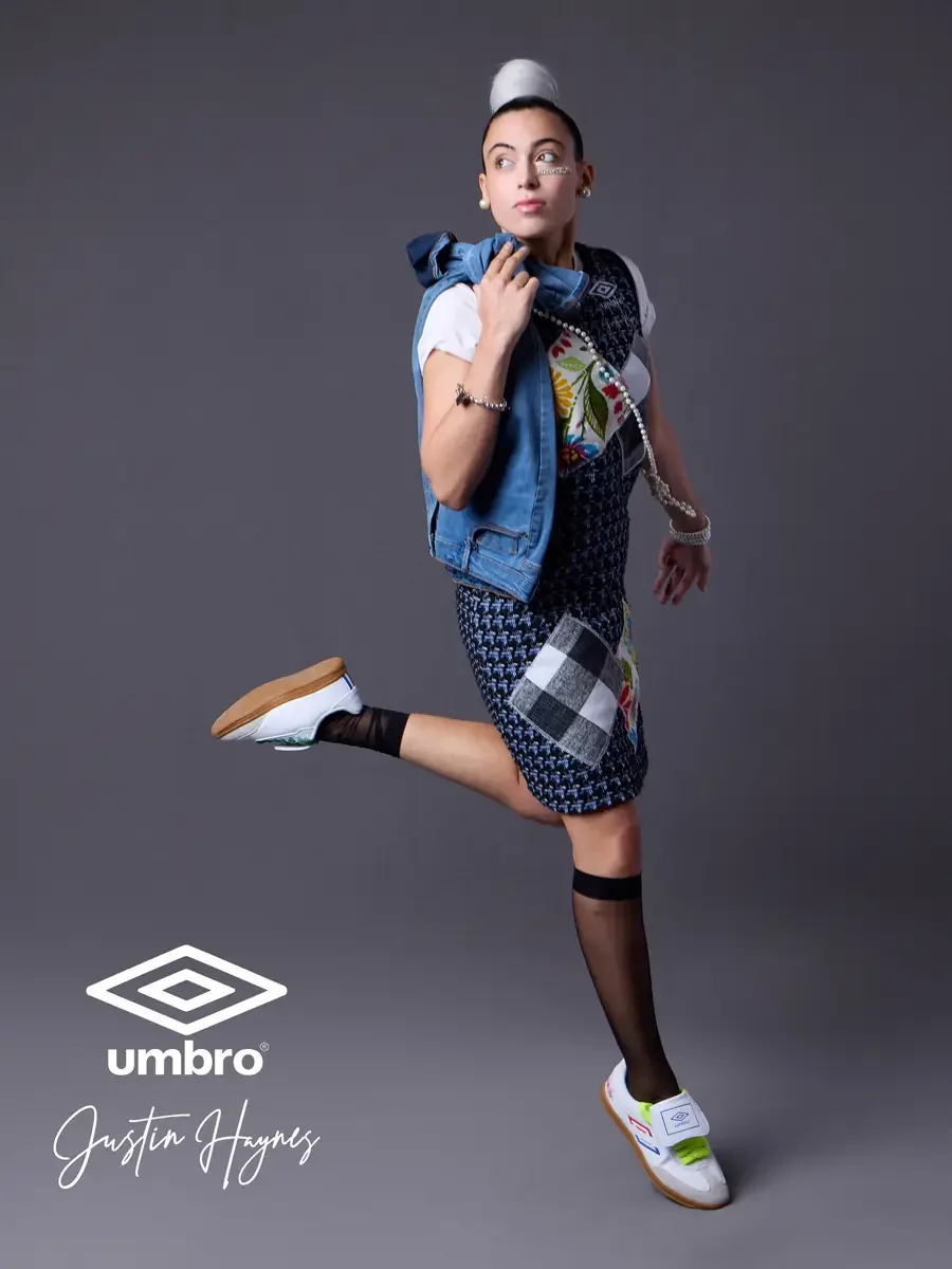 Elevated soccer style for the Umbro France collection. Vanessa mid-leap with a denim jacket draped over her shoulders in a navy houndstooth sleeveless shift dress with diagonal floral and patchwork panels layered over a white t-shirt, styled by Justi