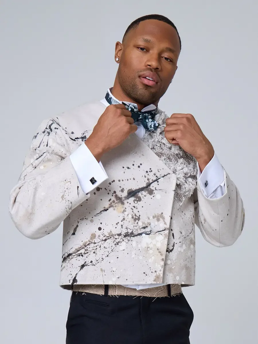 JUS10H 2025 New York Bridal Fashion Week, ivory abstract paint-splatter tuxedo jacket with dark teal floral bow tie and French cuff dress shirt with square cufflinks, photographed by Scott Parker Photo
