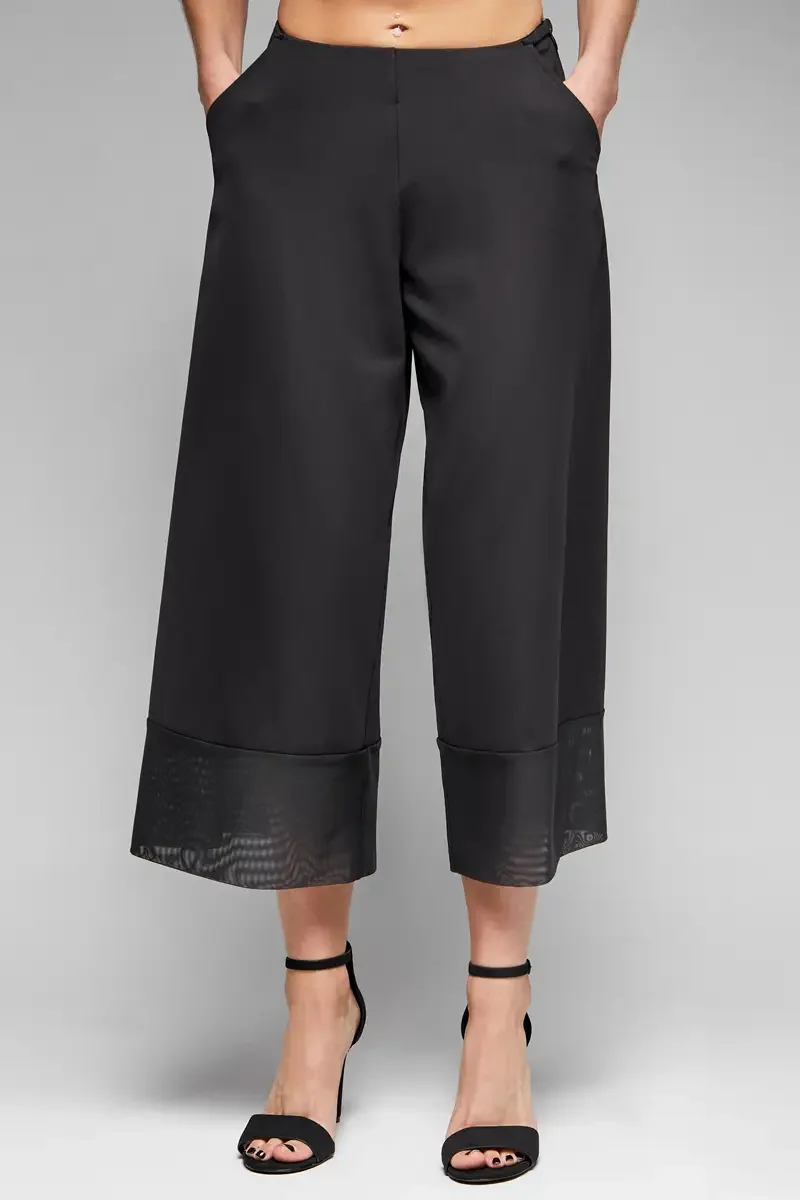 Minika Ko lookbook, detail, black wide-leg culottes, front view close crop of leg and sheer mesh cuff construction at hem, smooth synthetic fabric, photographed by Scott Parker Photo