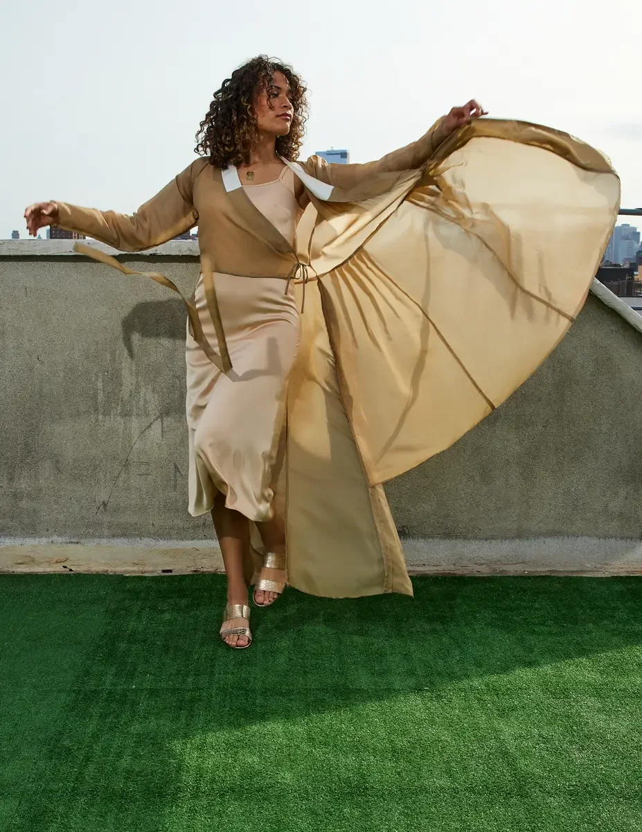 Fashion test shoot, full-length, model Ireland T in a gold satin wrap dress, skirt spreading wide in motion, East Village rooftop, New York City, styling by Matsine Stinson, makeup by Stefani Paige Vivian, photographed by Scott Parker Photo