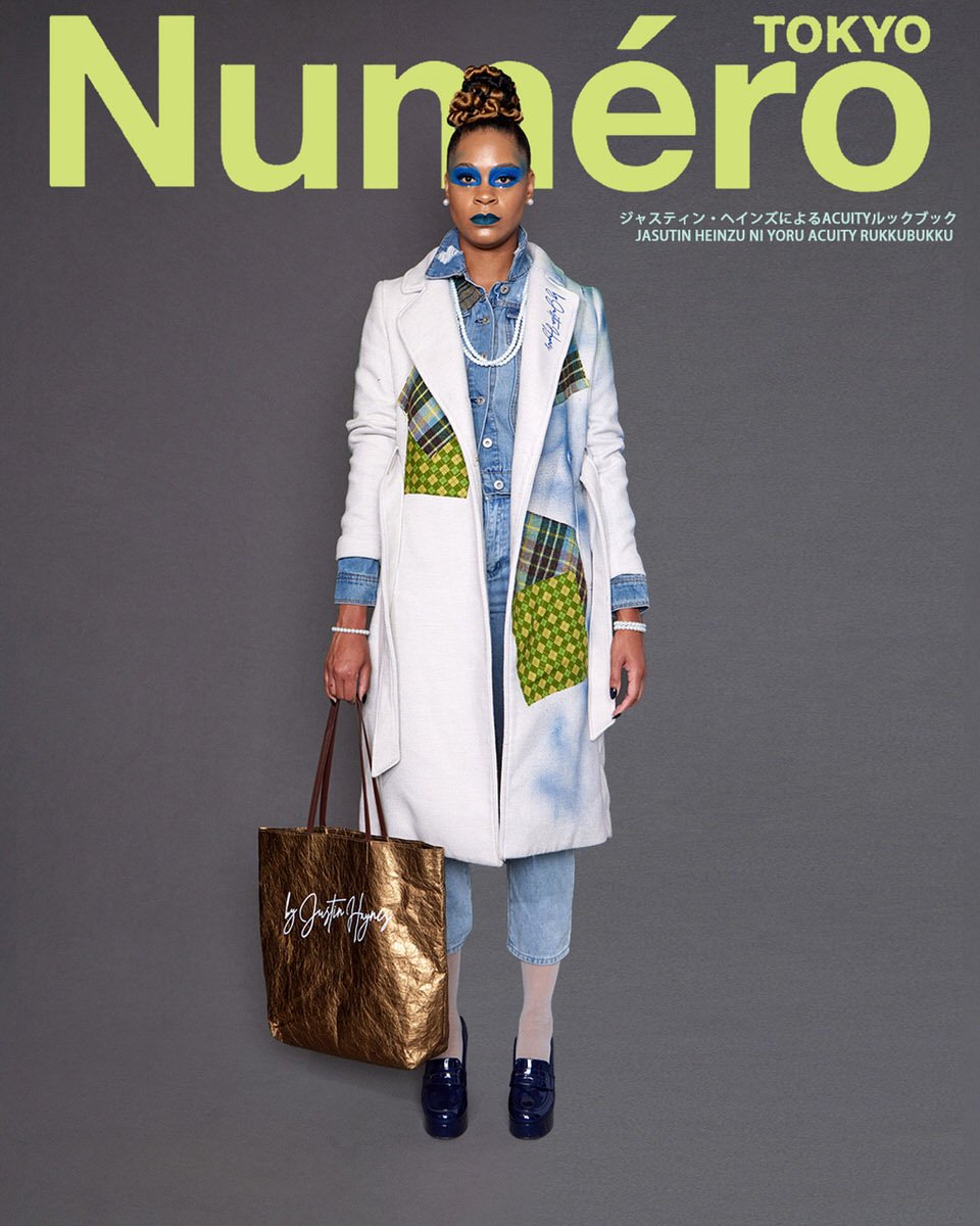 JUS10H by Justin Haynes ACUITY Collection lookbook for Numéro Tokyo by Scott Parker — model in cream wool overcoat with blue spray-paint detail and green checkered and tartan patchwork pockets, layered over chambray jumpsuit, paired with metallic gol