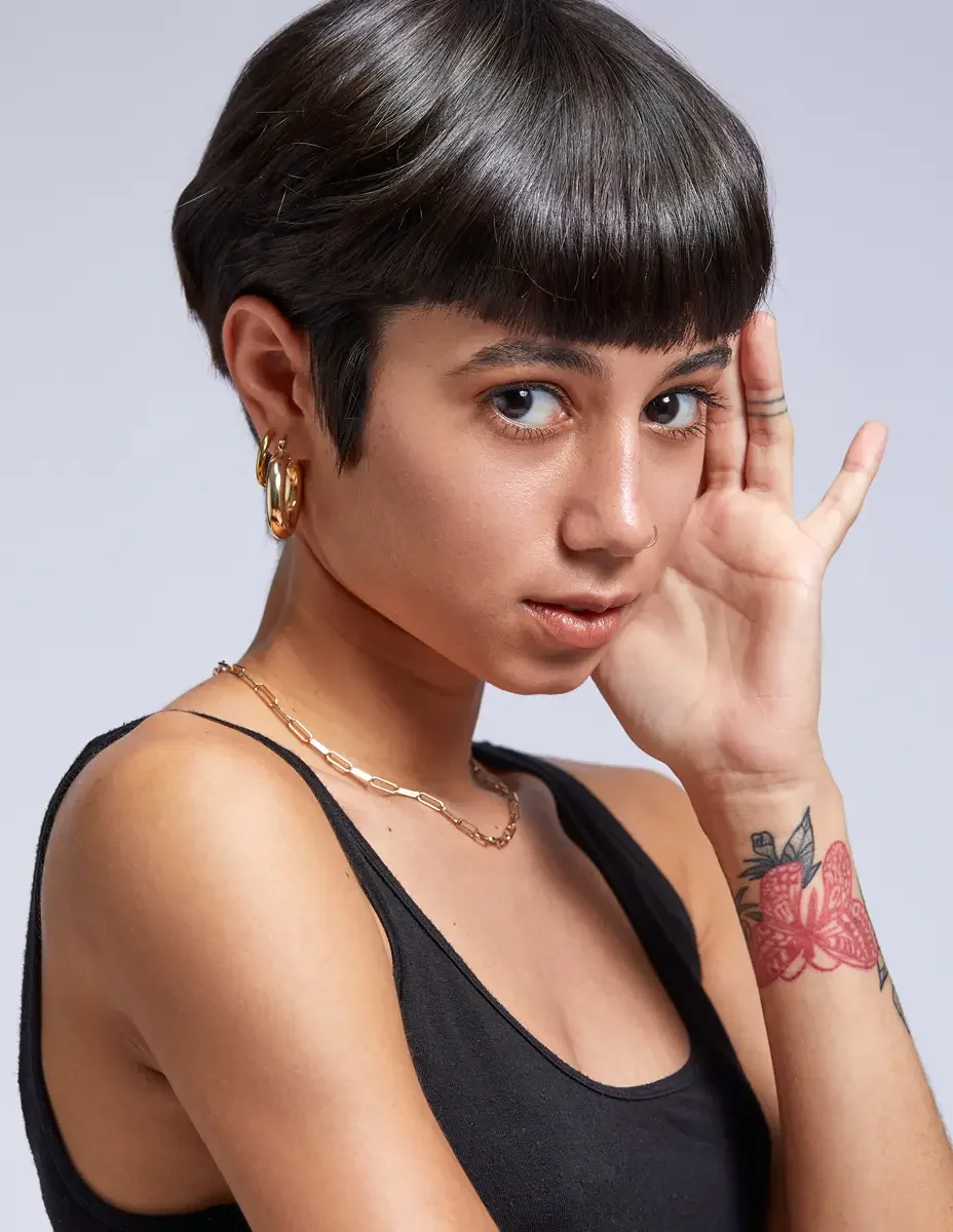 Eloissa, beauty portrait, gold hoop earrings and layered chain necklace, pixie cut with blunt fringe, floral wrist tattoo, East Williamsburg studio test shoot, makeup by Schanica Pickens, photographed by Scott Parker Photo