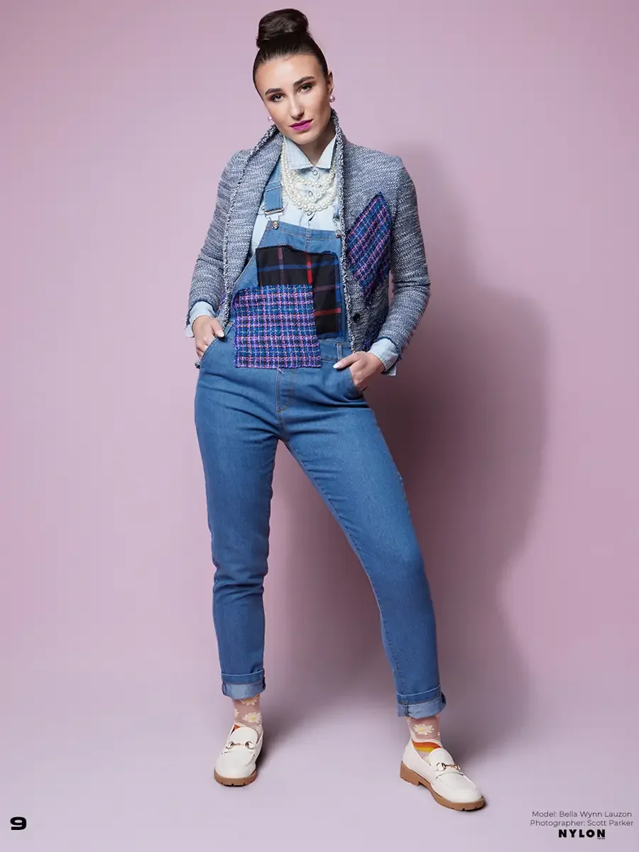 JUS10H 2025 Nylon Japan feature, model in grey fringe-trim boucle blazer with navy tartan and purple tweed patchwork panels over chambray shirt and blue denim overalls, layered pearl necklace, daisy sheer socks and white loafers, pink background, pho