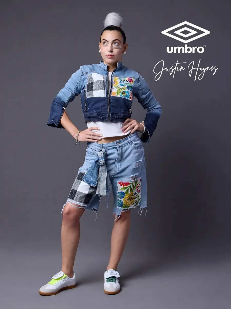 Fashion photographer producer and creative director work for the Umbro France collection. Vanessa standing with hands on hips and glancing sideways in a cropped two-tone denim moto jacket with floral patchwork panels and matching distressed denim ber