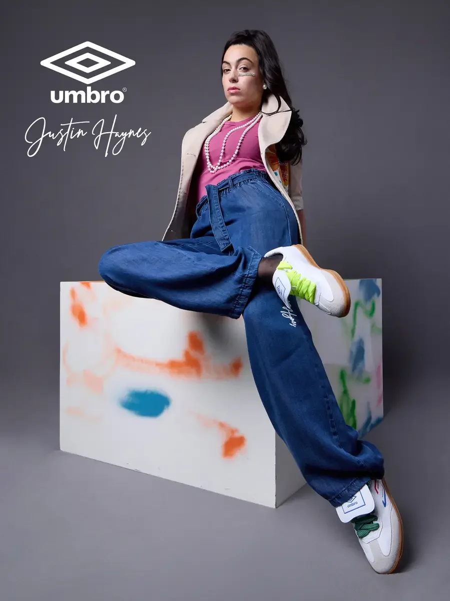  Fashion photographer producer and creative director work for the Umbro France collection. Vanessa reclined on a color-splashed prop with one leg raised and gazing away in a sand utility jacket with floral patchwork panels over a fuchsia t-shirt and 
