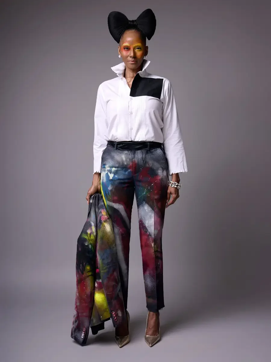 JUS10H Met Monday 2026, full-length hand-painted suit, blazer carried at side, white tuxedo shirt and painted trousers, grey background, photographed by Scott Parker Photo