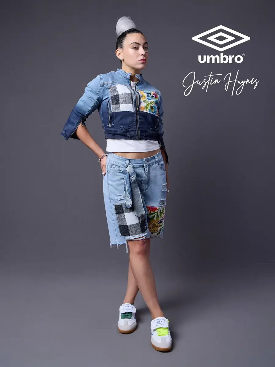Fashion lifestyle photography for the Umbro France collection. Vanessa in a three-quarter stance with one hand on hip in a cropped two-tone denim moto jacket with floral patchwork panels and matching distressed denim bermuda shorts, styled by Justin 