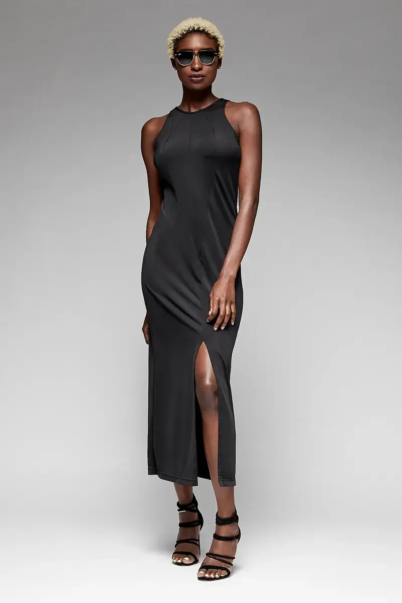Minika Ko lookbook, black sleeveless jumpsuit, front view, high halter neckline with angled seam detail at shoulder, side slit at hem, smooth synthetic fabric, dark sunglasses, photographed by Scott Parker Photo