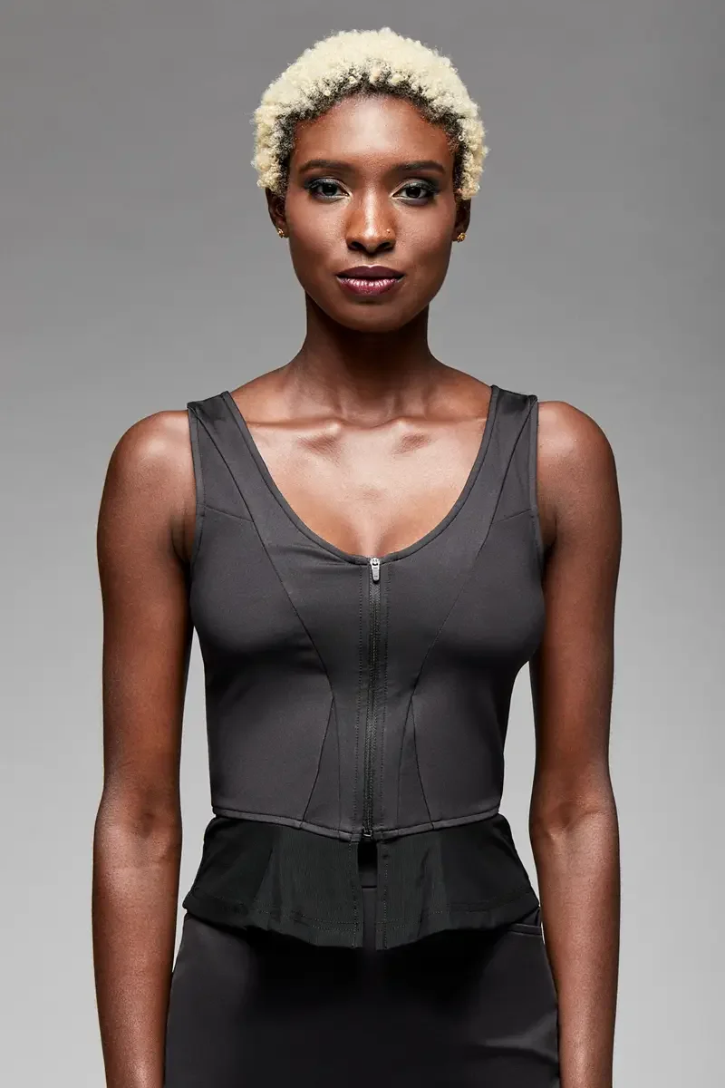 Minika Ko lookbook, detail, black zip-front corset top, close crop showing scoop neckline, center front zip, boning seam construction, and peplum ruffle at waist, photographed by Scott Parker Photo