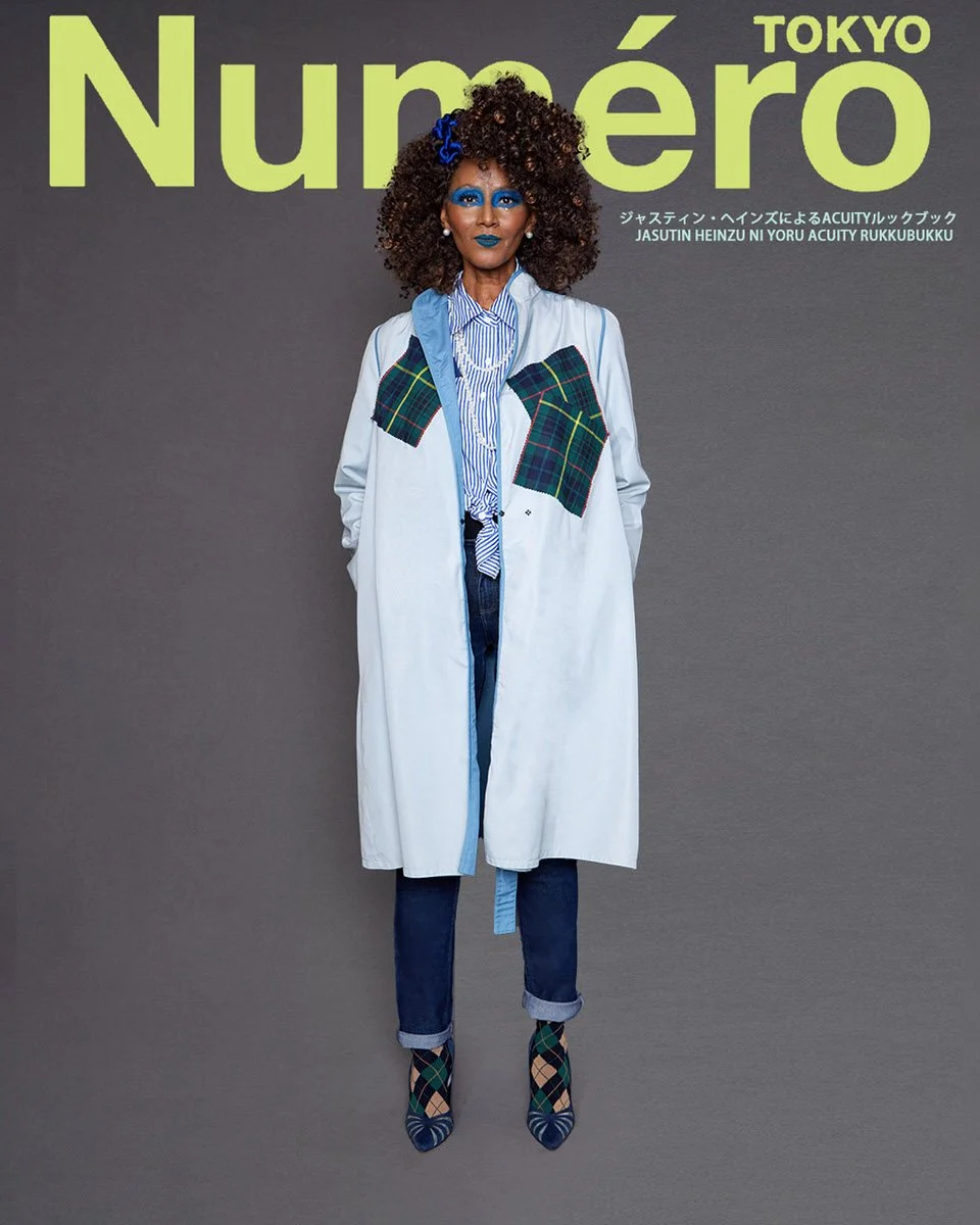JUS10H by Justin Haynes ACUITY Collection lookbook for Numéro Tokyo by Scott Parker — model in pale blue duster coat with green tartan chest patch pockets, layered over blue and white striped tie-front blouse, dark wash cuffed jeans, pearl necklace, 