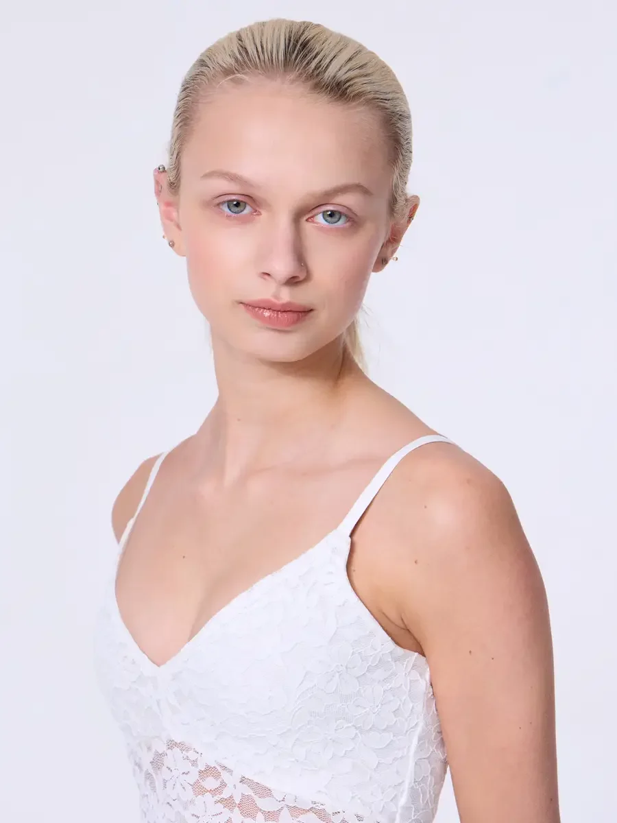 Model portfolio development session, commercial look, white lace crop camisole top with floral lace detail and V-neckline, close-crop, hair pulled back sleek, direct gaze slightly off-axis, light gray background, photographed by Scott Parker Photo, N