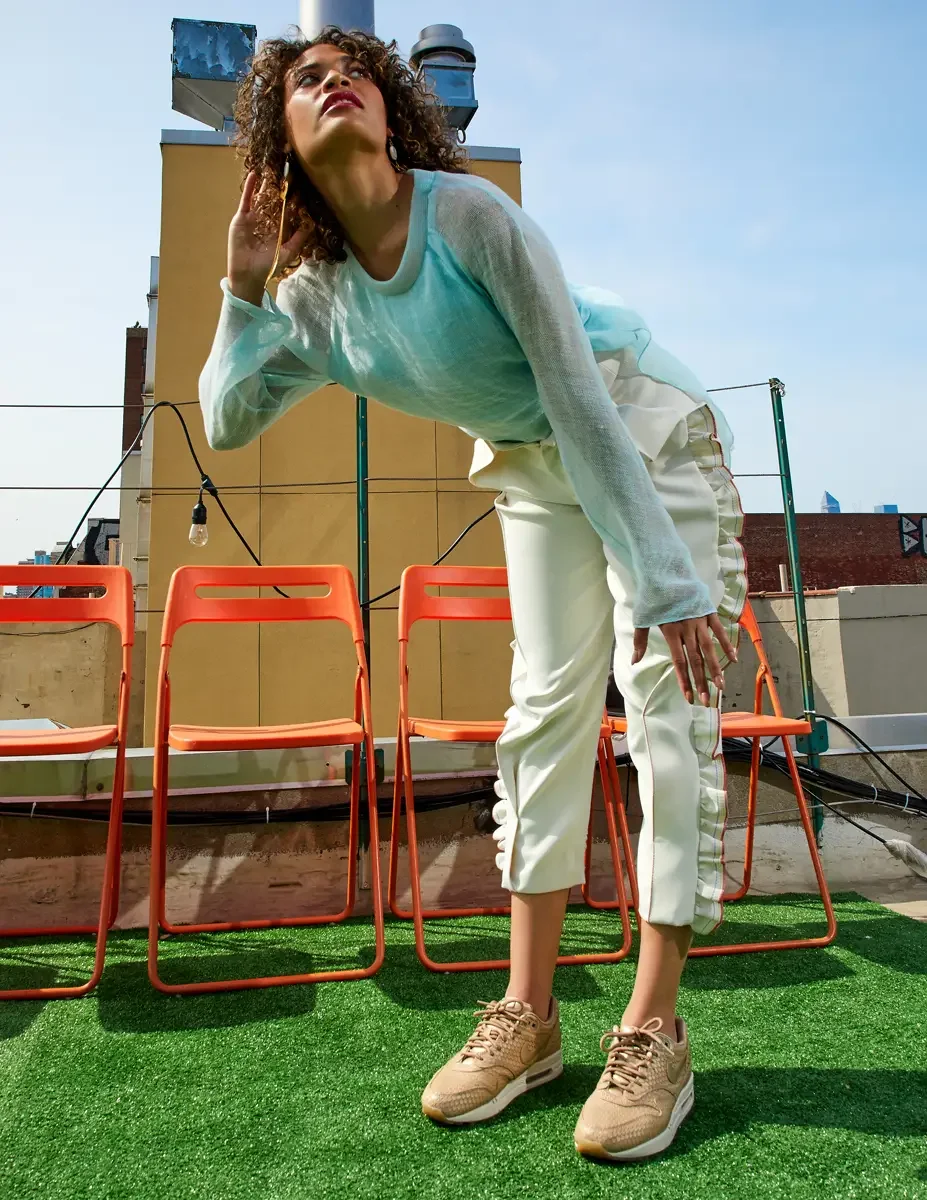 Fashion test shoot, full-length, model Ireland T in Amy Page DeBlasio white ruffle-trim pants and aqua sheer knit top, East Village rooftop, New York City, styling by Matsine Stinson, makeup by Stefani Paige Vivian, photographed by Scott Parker Photo