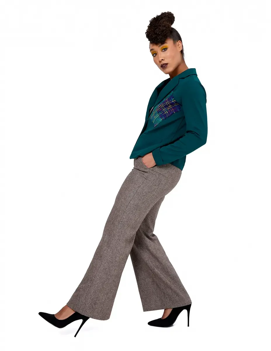 Model portfolio development session, high fashion editorial look, teal single-button blazer with multicolor tweed appliqué panel, wide-leg heather tan orange trousers, black stiletto heels, full-length, profile, hand in pocket, gaze over shoulder, wh