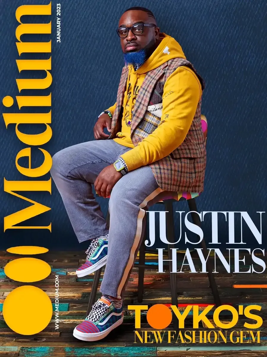 JUS10H 2023 Medium Magazine feature, editorial cover, mustard hoodie under plaid vest, seated portrait on reclaimed wood floor, photographed by Scott Parker Photo