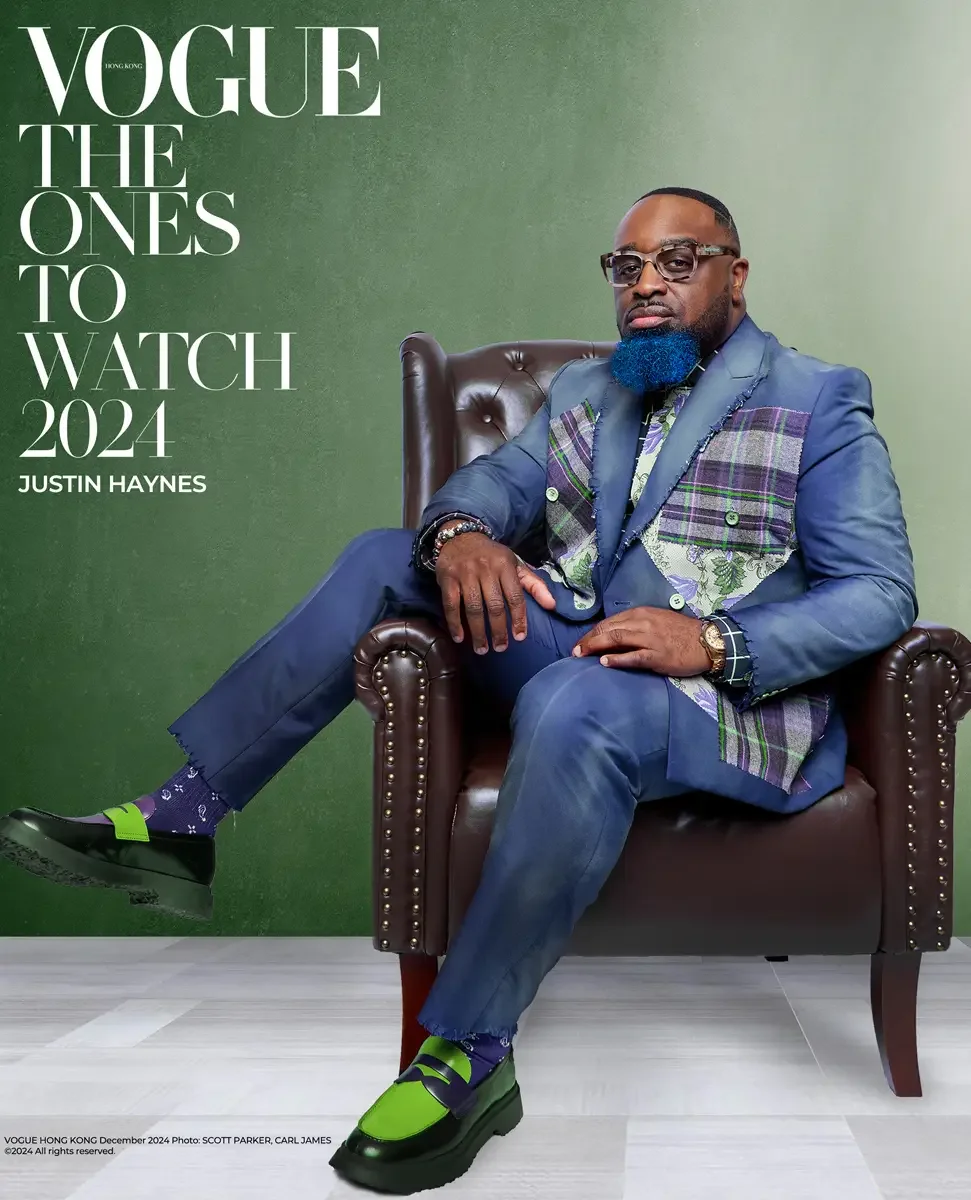 JUS10H 2024 Vogue Hong Kong feature, The Ones to Watch, seated editorial portrait, navy patchwork suit with plaid detail, leather armchair, green background, photo credit Scott Parker, photographed by Scott Parker Photo