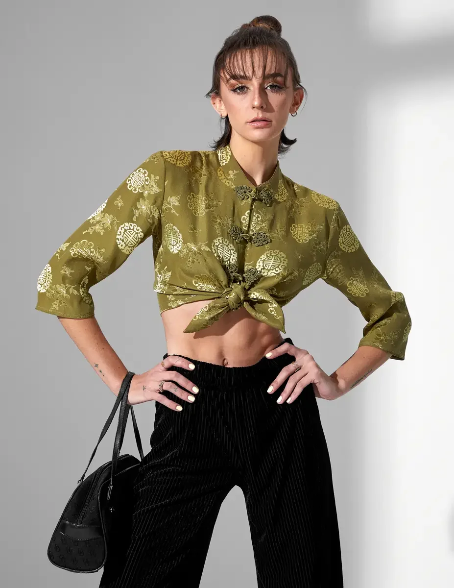 Macy, three-quarter crop, hands on hips, olive green satin jacquard tied crop top with gold medallion print and frog closures, black wide-leg ribbed velvet culottes, black suede barrel bag, New York studio test shoot, photographed by Scott Parker Pho