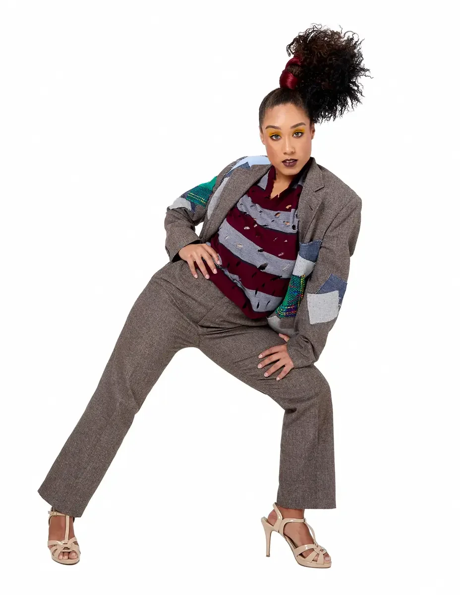 Model portfolio development session, high fashion editorial look, oversized heathered blazer with mixed fabric appliqué panels over burgundy and heather grey destroyed-knit stripe sweater with raw-edge sleeves, straight-leg heathered trousers, nude t