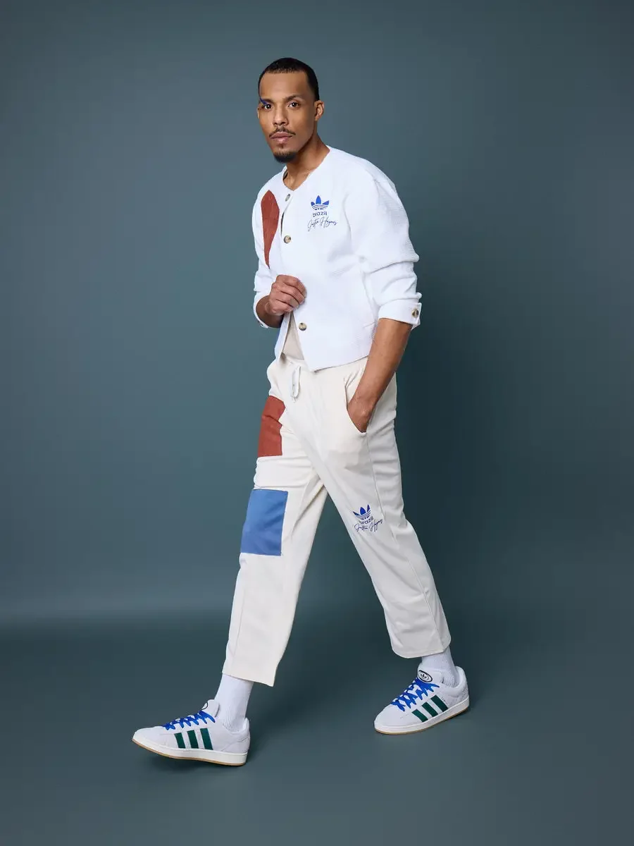 JUS10H x Adidas Brasil campaign, model in mid-stride walking pose pulling cardigan closed, white textured patchwork cardigan with terracotta suede panel over cream patchwork drawstring trousers with blue and terracotta panels, Adidas Campus 00s in wh